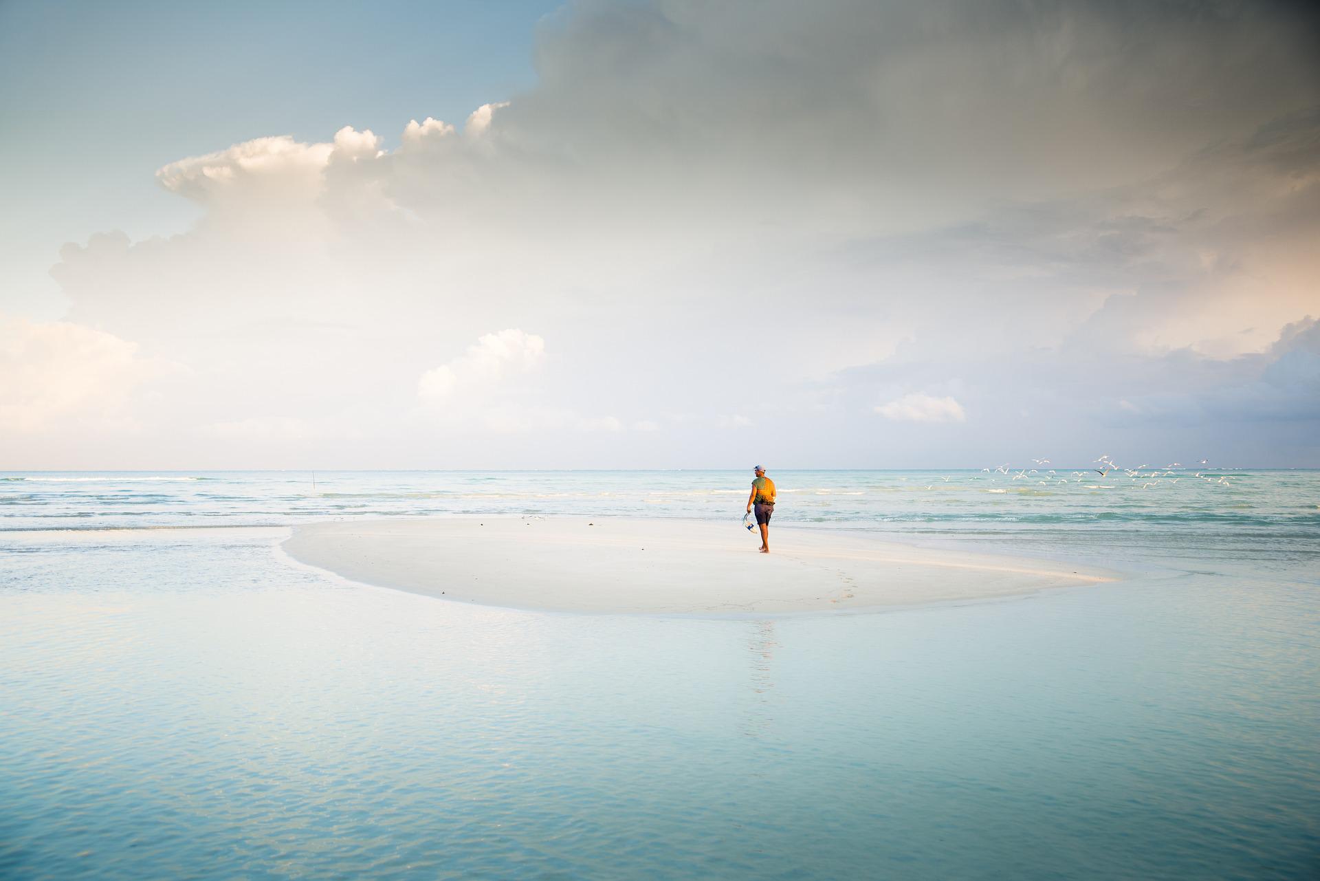 man in the middle of sand island on beach